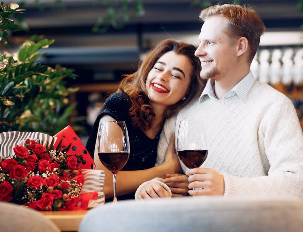 Couple in a restaurant. Lady in a black dress. Woman drinking a vine