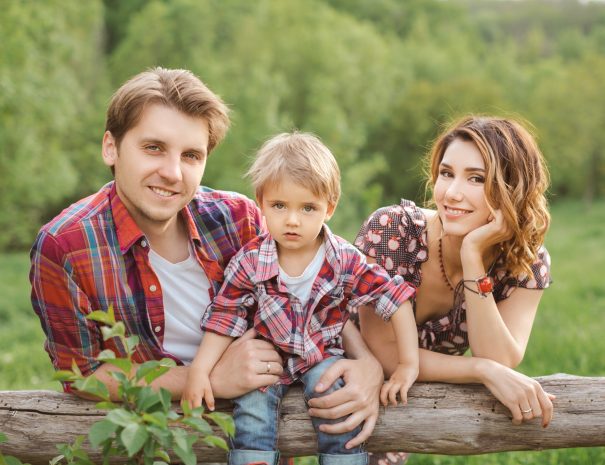 Happy Family on the nature. Mother father and son in casual clothes, sit on a fence, rural look , outdoors